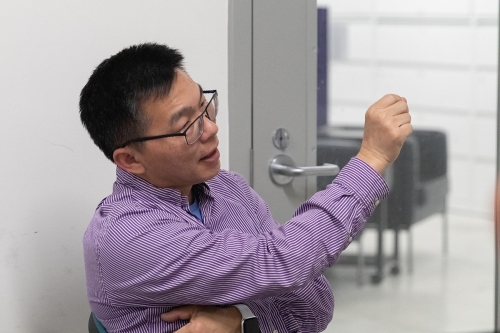 Professor Zhang wearing a collared shirt, talking with his hand outstreched