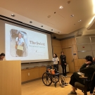 people in a classroom during a presentation where a wheelchair sits at the front