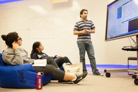 Students at the Student Startup Center in front of a white board discussing a problem