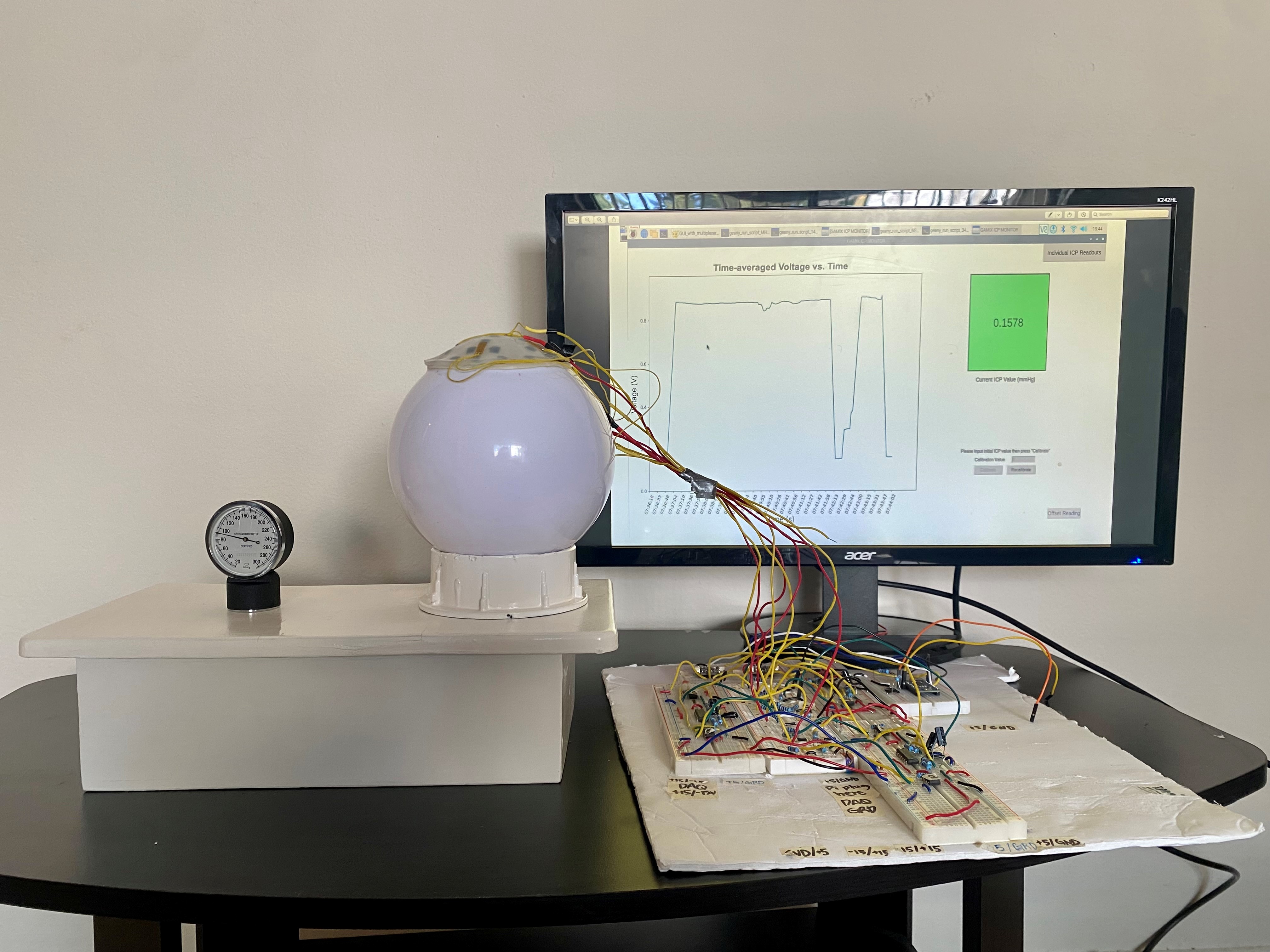 Sphere with wires connected to the top sits on a desk with a computer screen showing a graphic