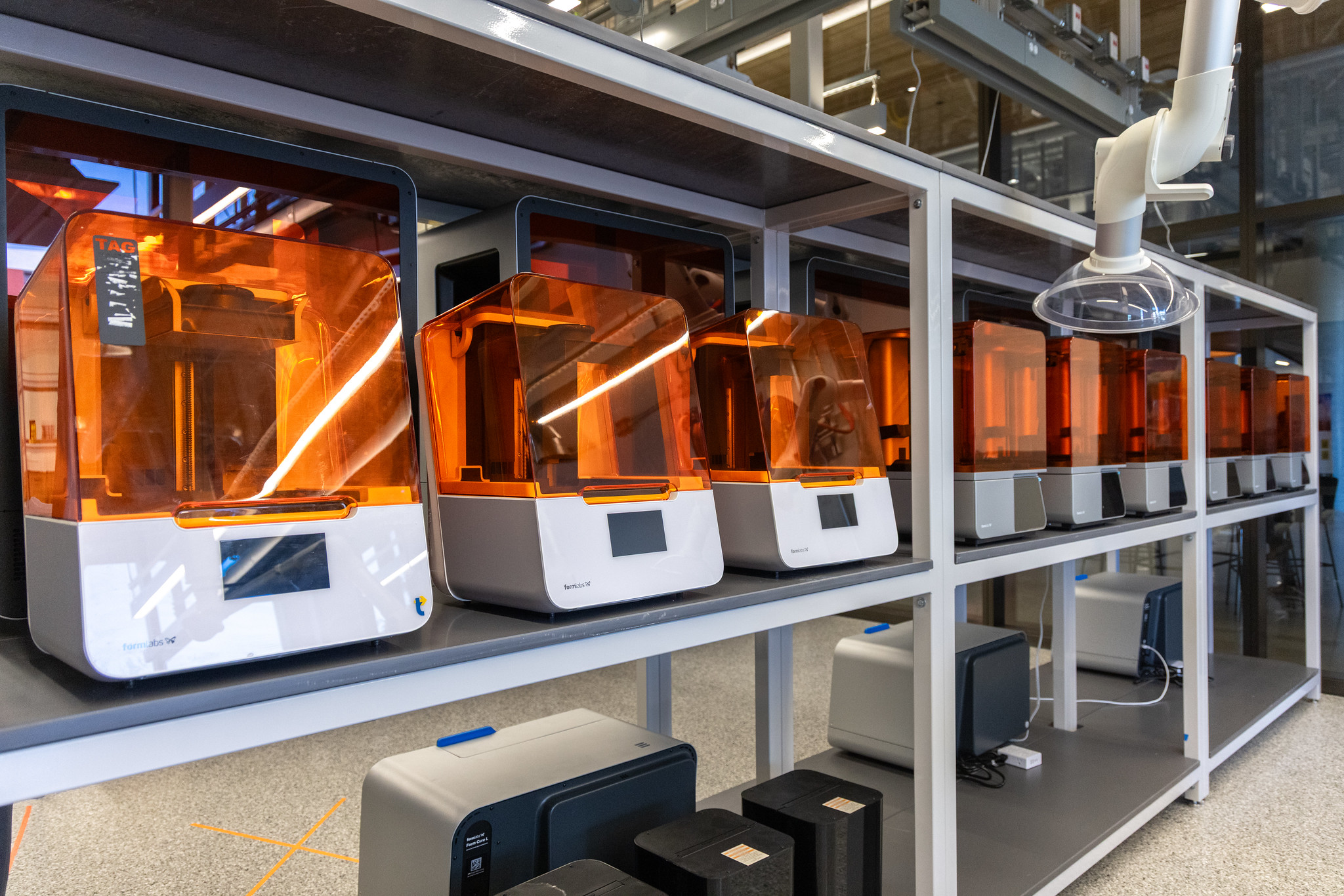3D printers in a row with bright orange covers