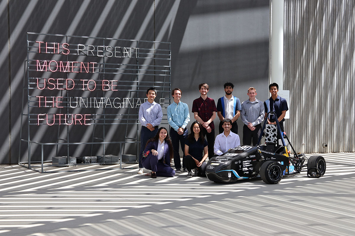 Graduating senior members of Formula Racing pose with their vehicle outside of Manetti Shrem