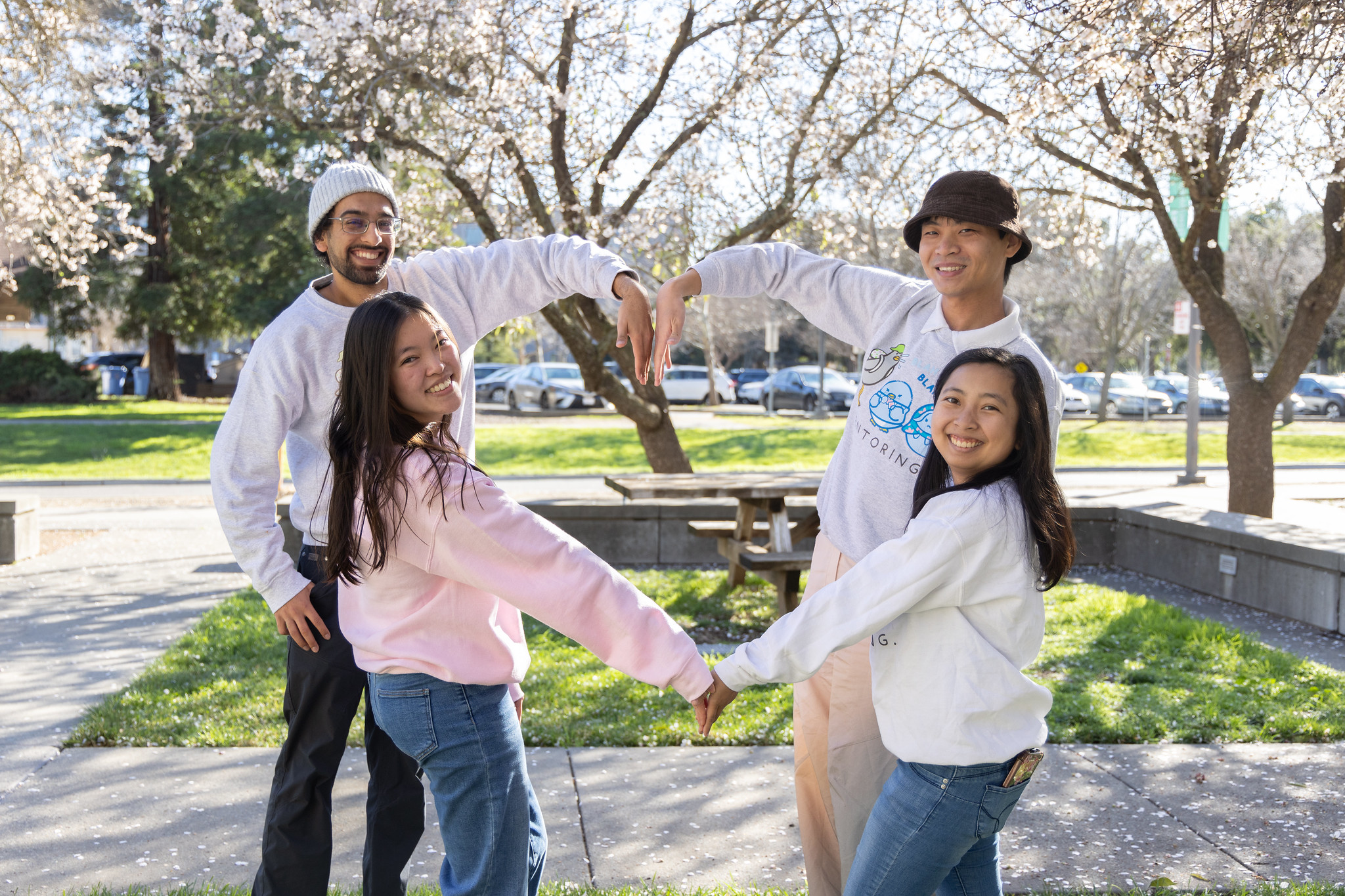 Four students forming a heart with their arms