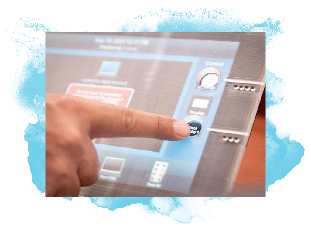 Screen with plastic overlay and a finger pressing an icon on the screen