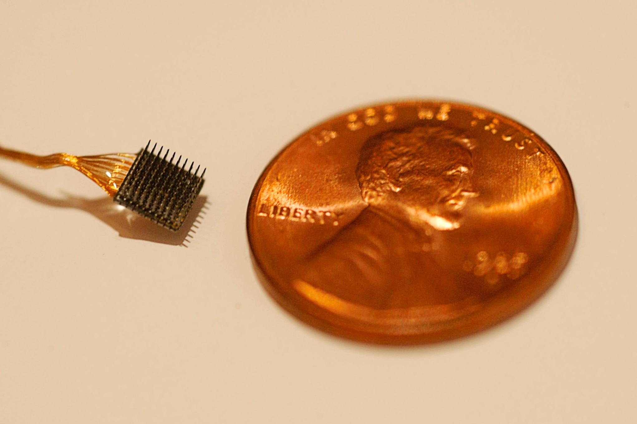 Wired electrode sitting near US Penny