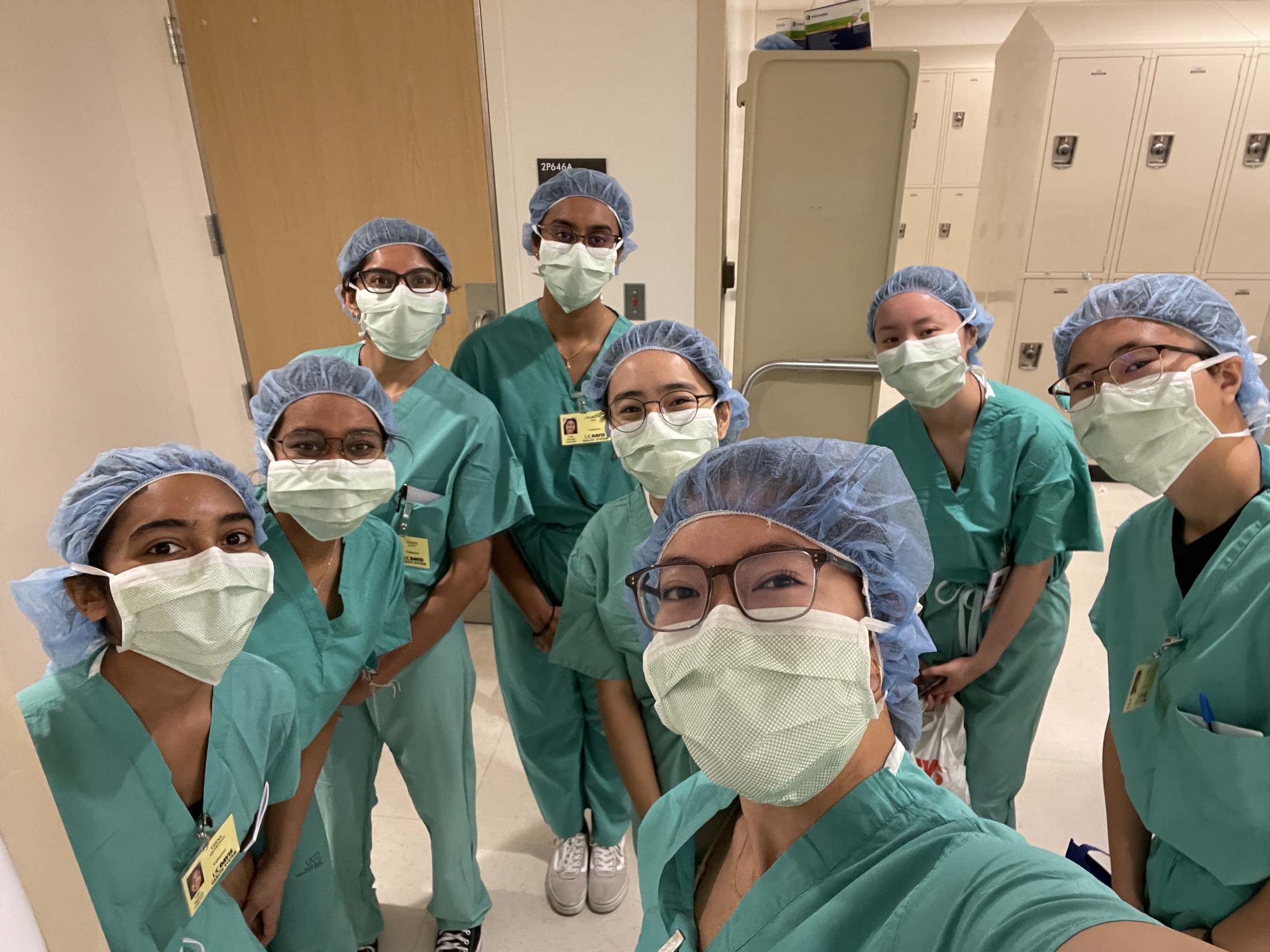 Students huddle for a group selfie wearing medical PPE