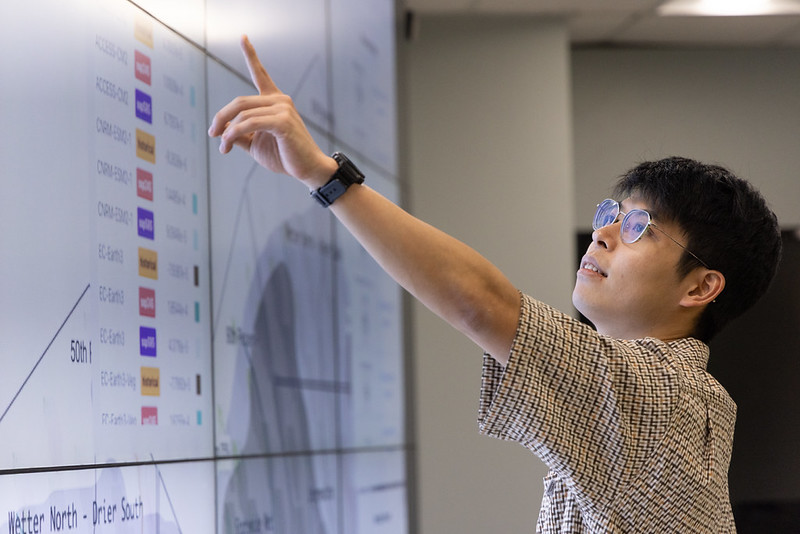 Kawakami pointing at large presentation screen.