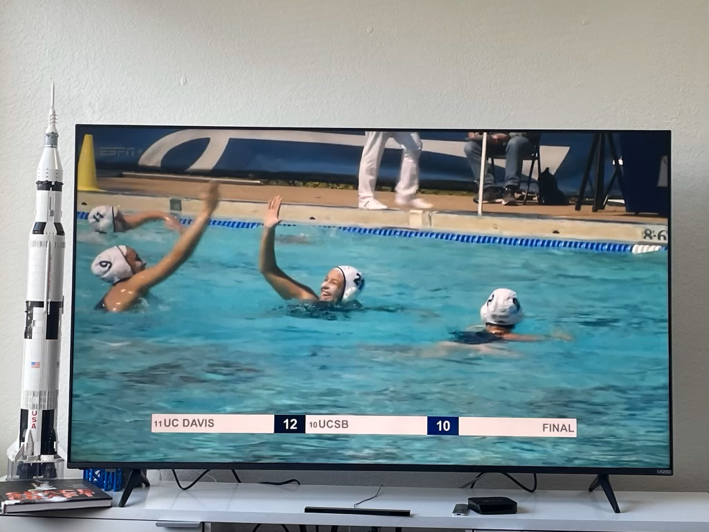 TV showing a water polo game where two team members are high fiving each other