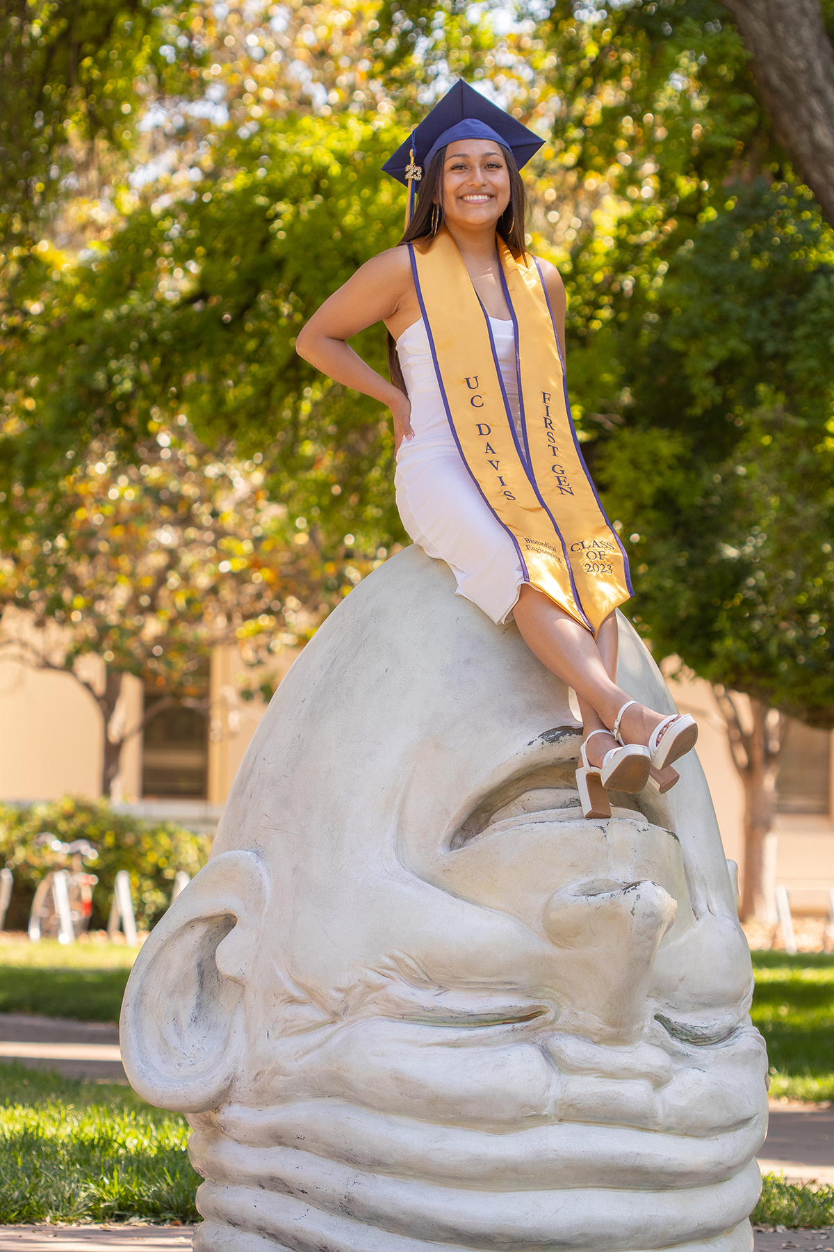Blanca Osorio sitting on sculpture of an egg head on the UC Davis campus