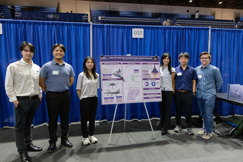 Student team standing by a research poster in a hall with curtains
