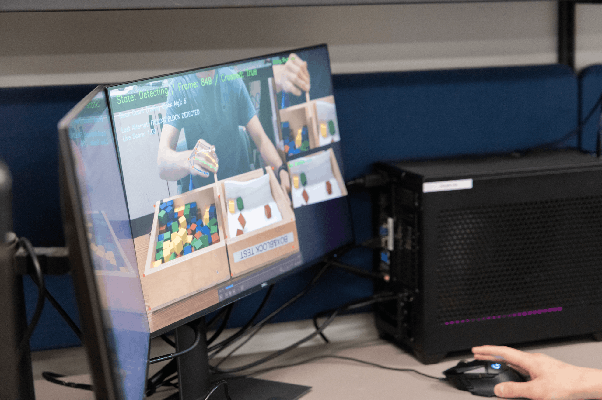 Computer monitor displaying a program tracking hands sorting colorful blocks.