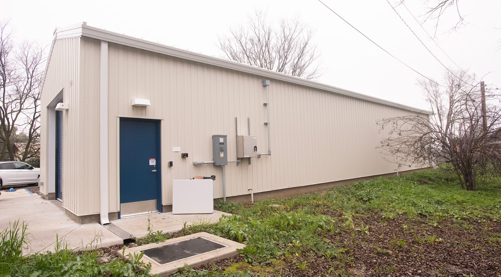 A modest, light-colored metal building with a blue door 