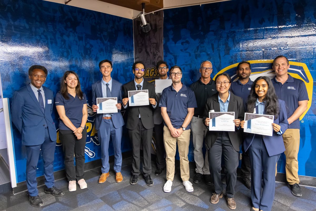 Team members hold certificates and stand with judges for a photo