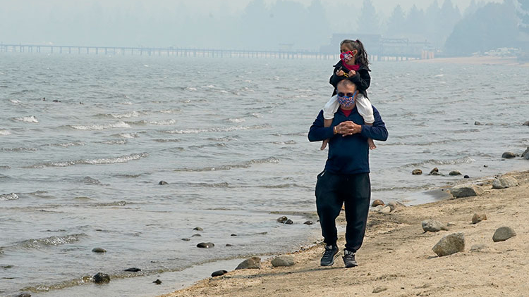 Dad and daughter walking on beach with mask on