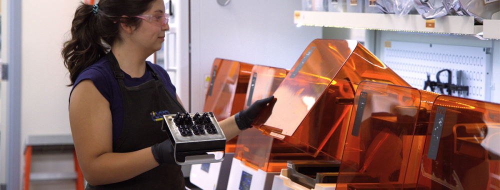 Valerie Quiroz working with orange 3D printers
