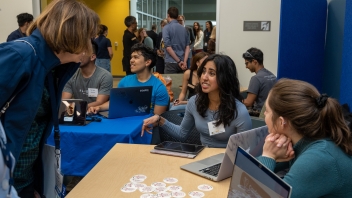 A female student presents a team project in a crowded room