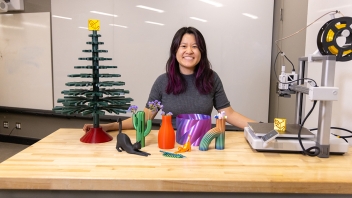 Vivian Vuong stands at a table with her designs