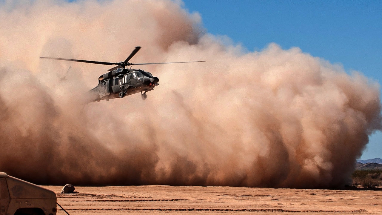Helicopter emerging from a dust cloud against a blue background