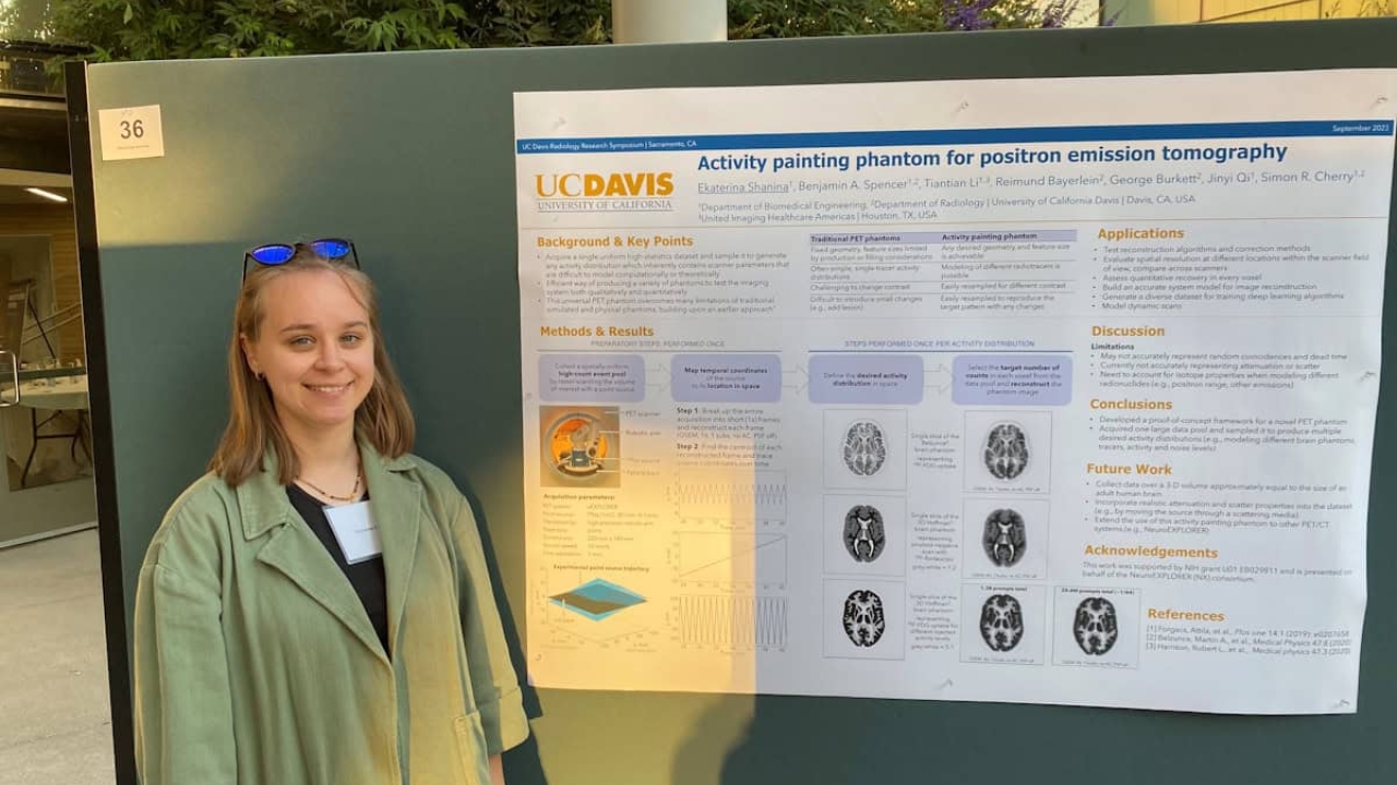 Ekaterina stands next to poster