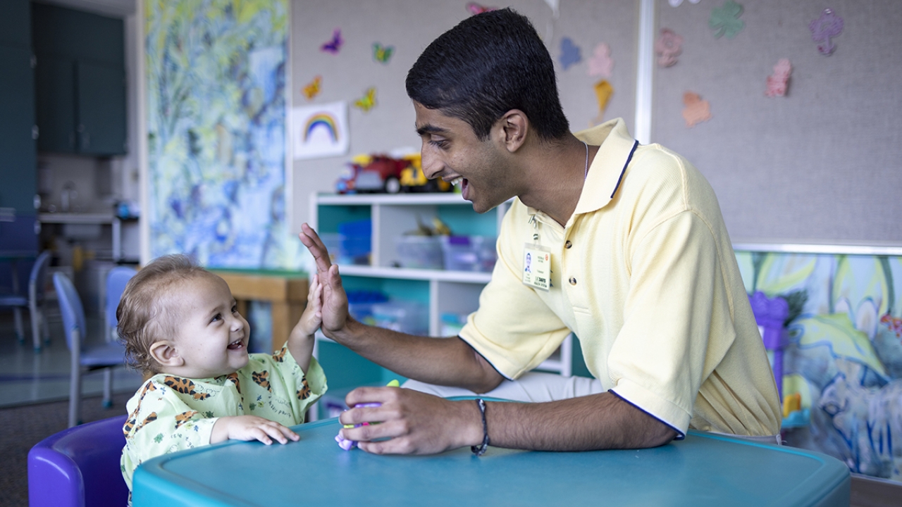 UC Davis student Neeraj Senthil high fives a child at a children's hospital