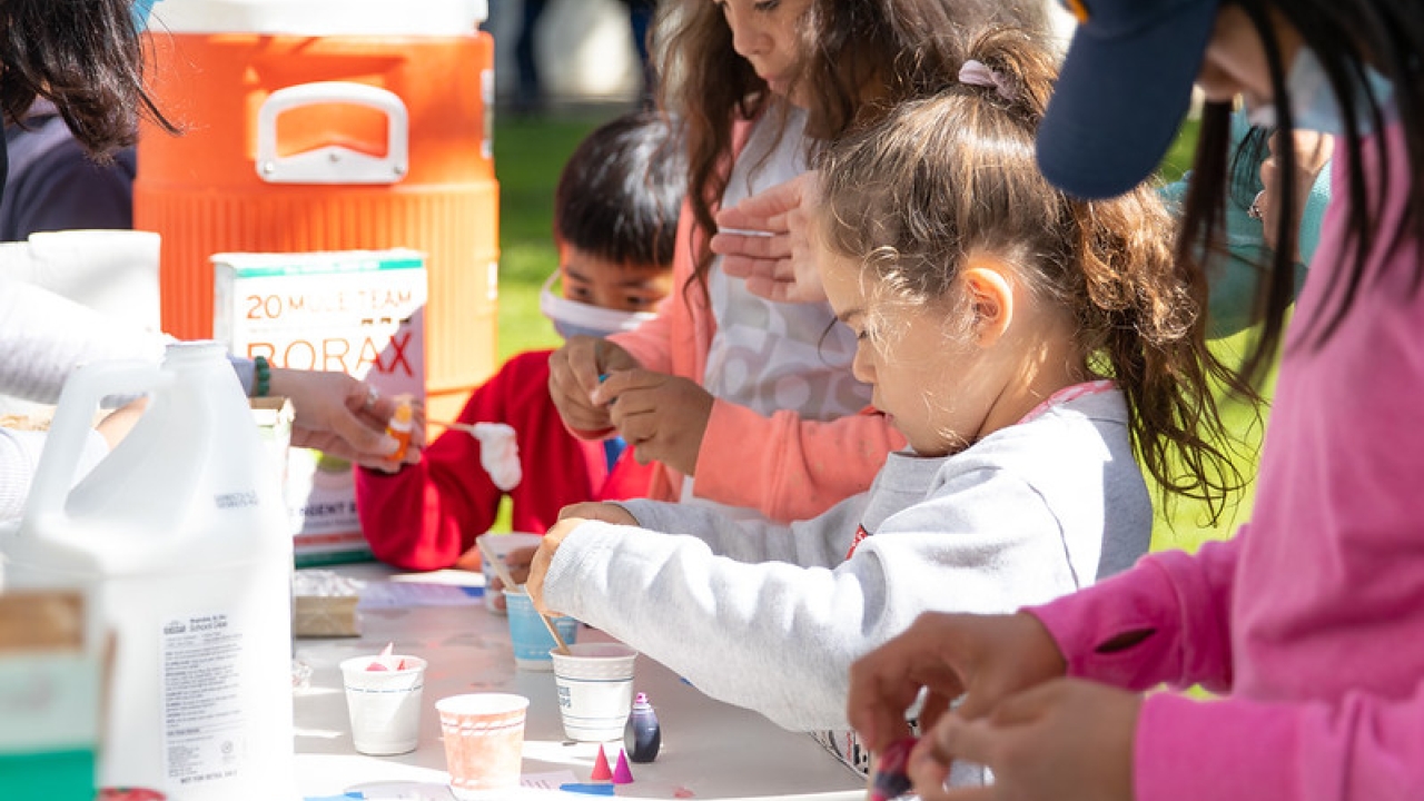 Children at table outside making silly putty at UC Davis Picnic Day