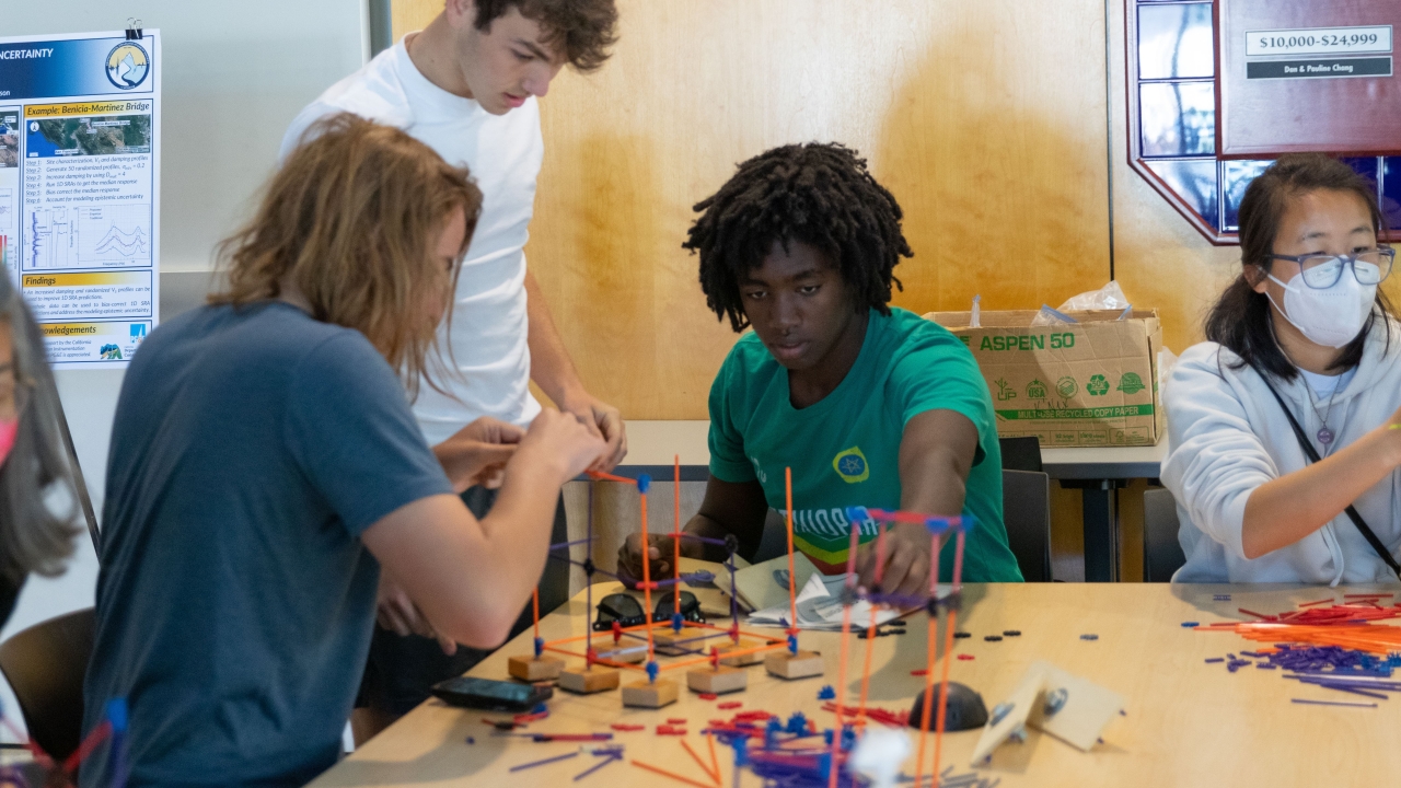 Three people creating a miniature building structure