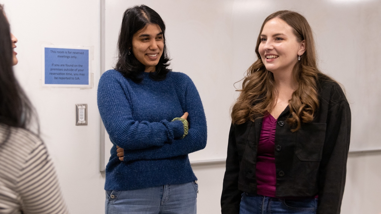 Three women standing indoors talking to each other at a COFFEE at UC Davis Meeting