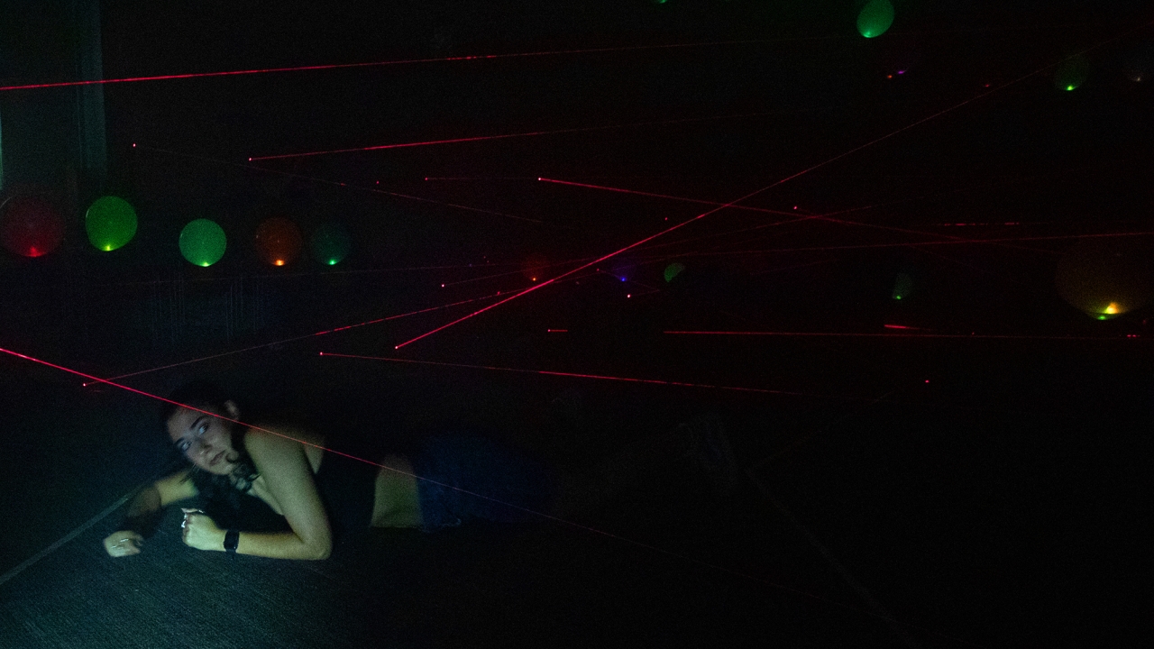 A woman crawling under a laser beam