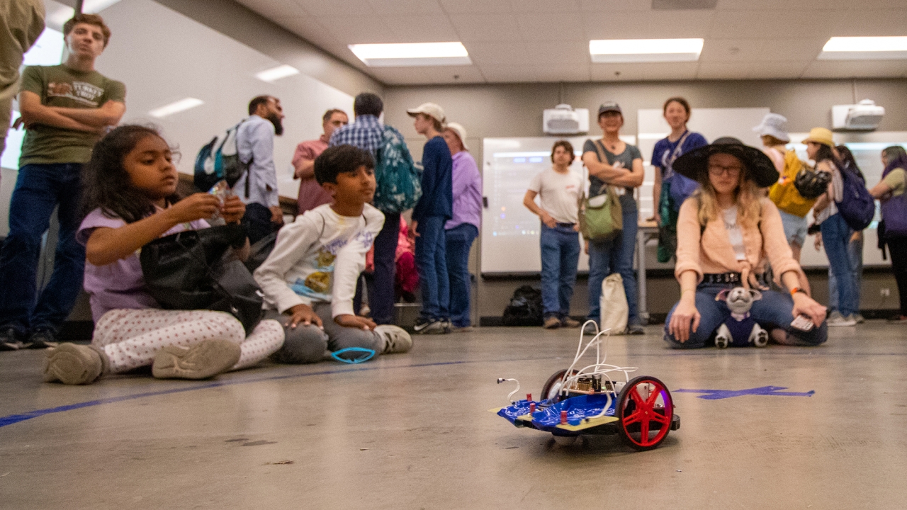 A crowd watching a small robotic car