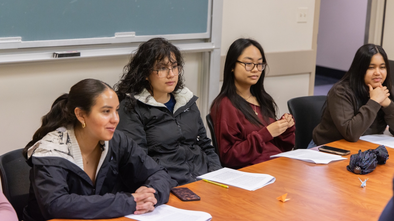 Four students gather around a table in conversation