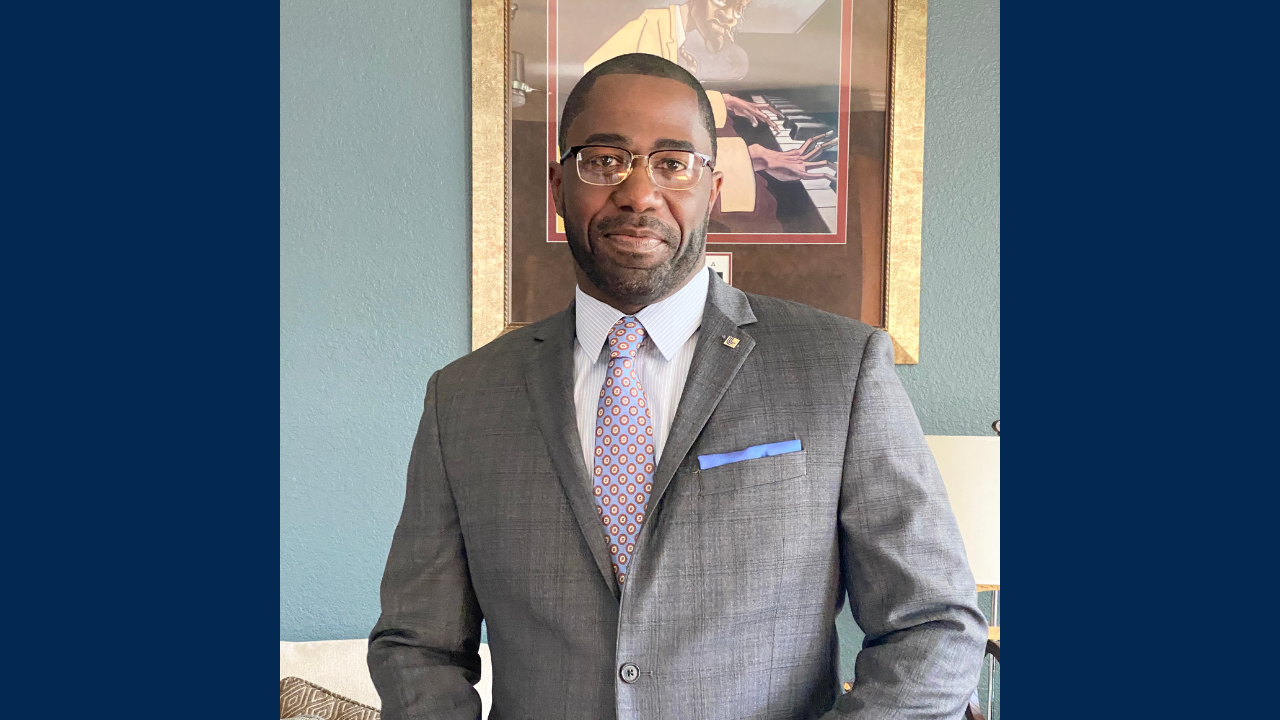 Kevin Griffin wears a suit indoors near artwork on wall