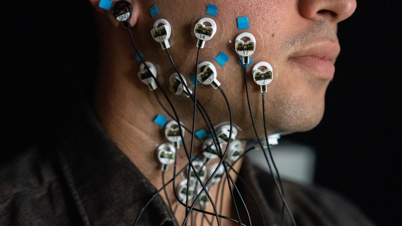 A man's cheek is covered in electrodes