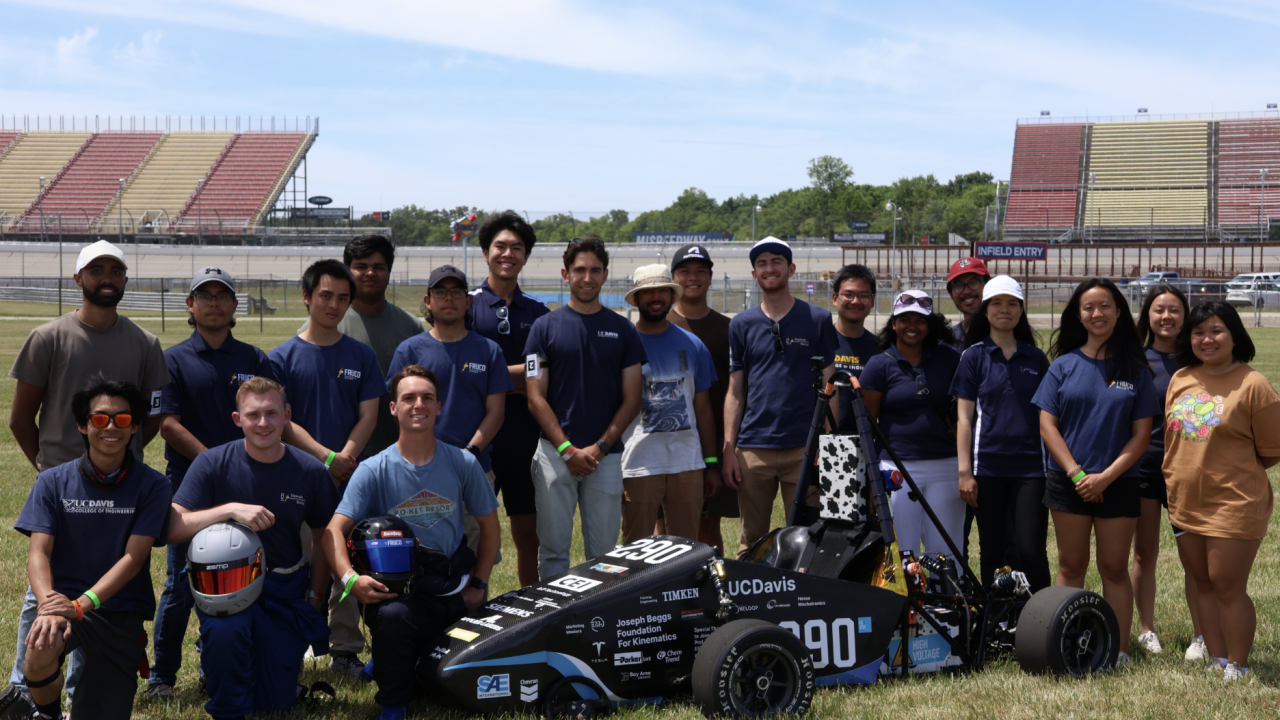 Formula Racing team standing around a medium-sized racing car