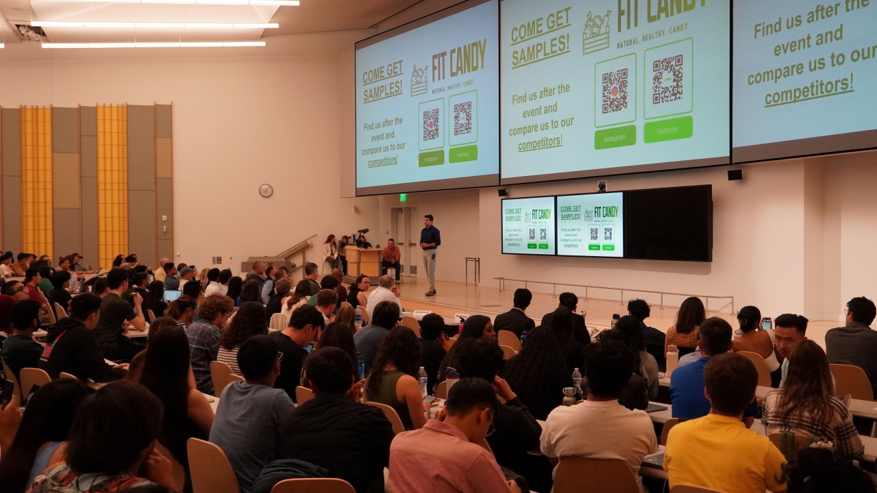 A student presents on stage in front of a full audience