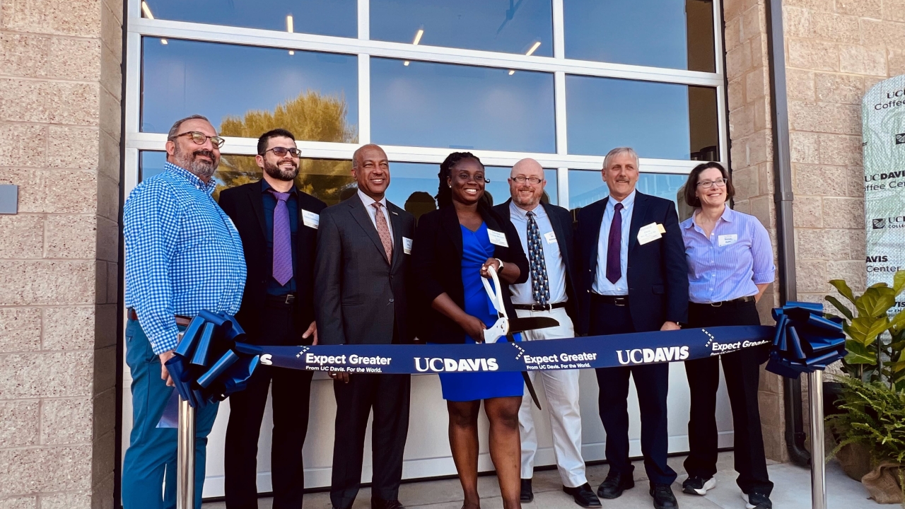 Seven people stand in front of the coffee center at a ribbon cutting ceremony