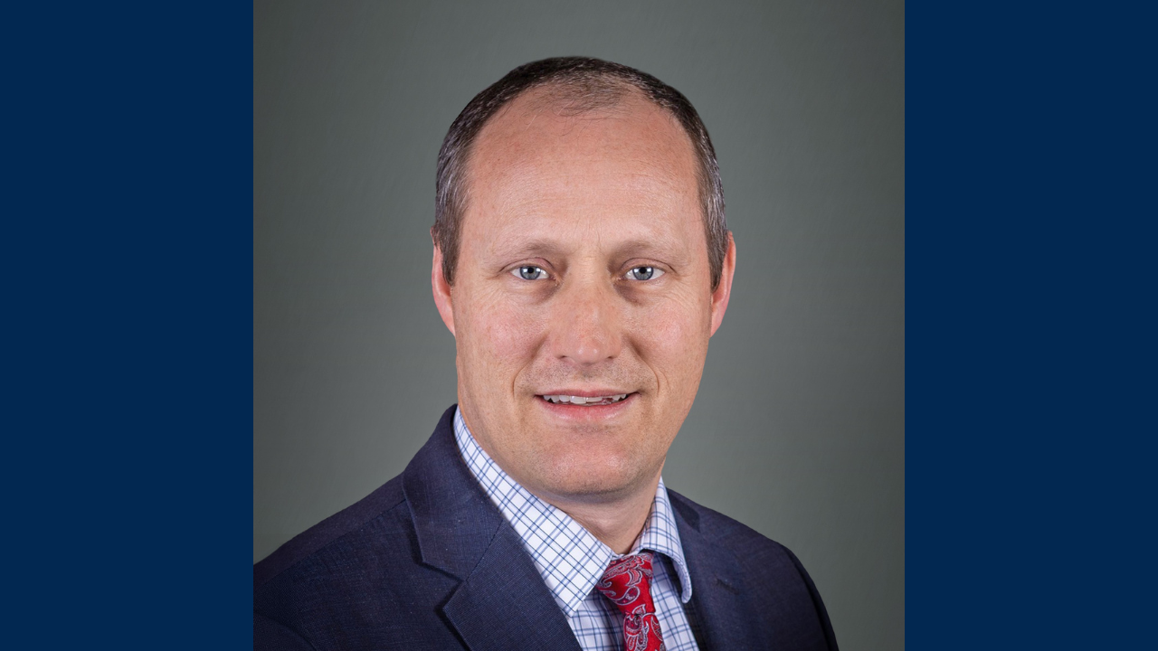 Professional headshot of Jeramy Decker in a suit and tie