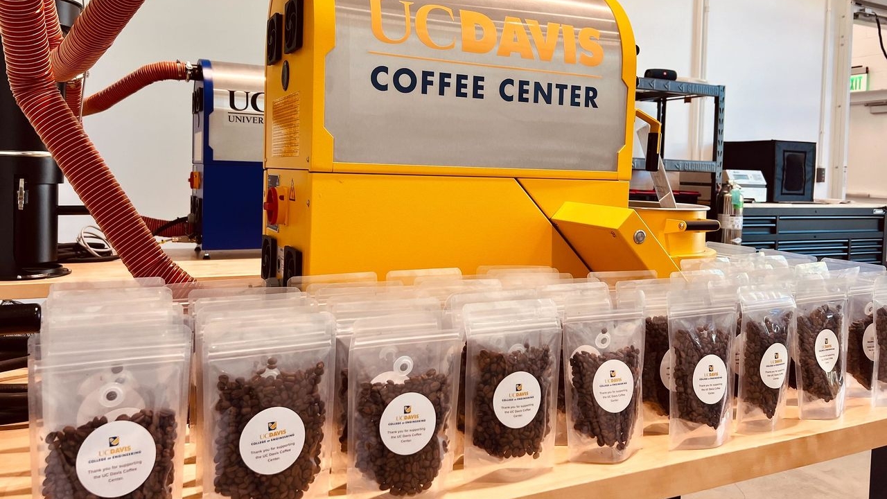 Many bags of coffee beans in front of a large yellow Coffee Center machine