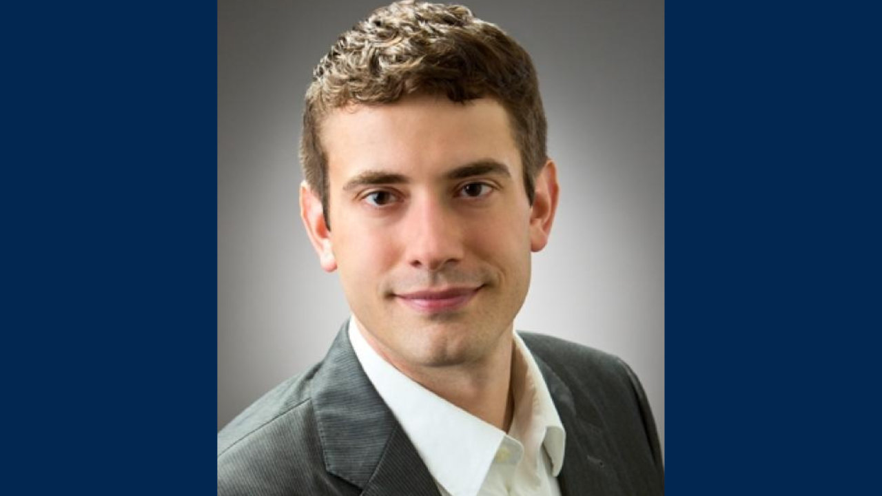 A portrait of a man wearing a suit against an all blue background