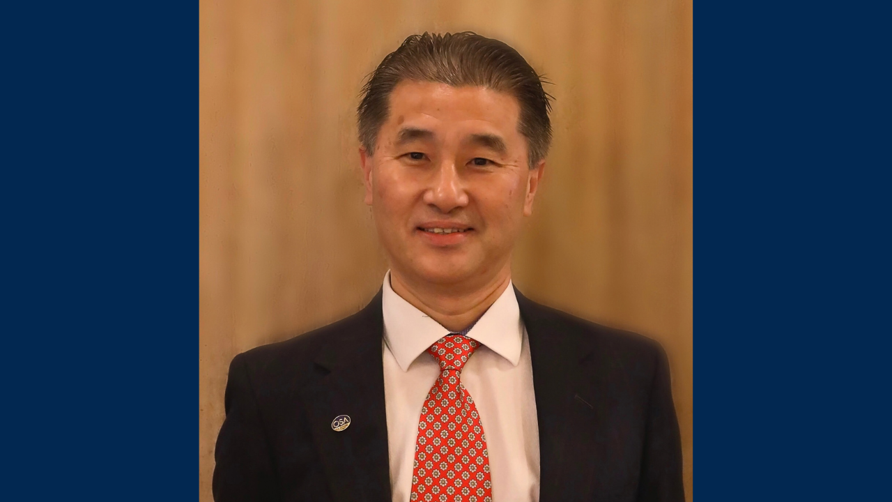 Professor Xiangdong Zhu smiling on brown background