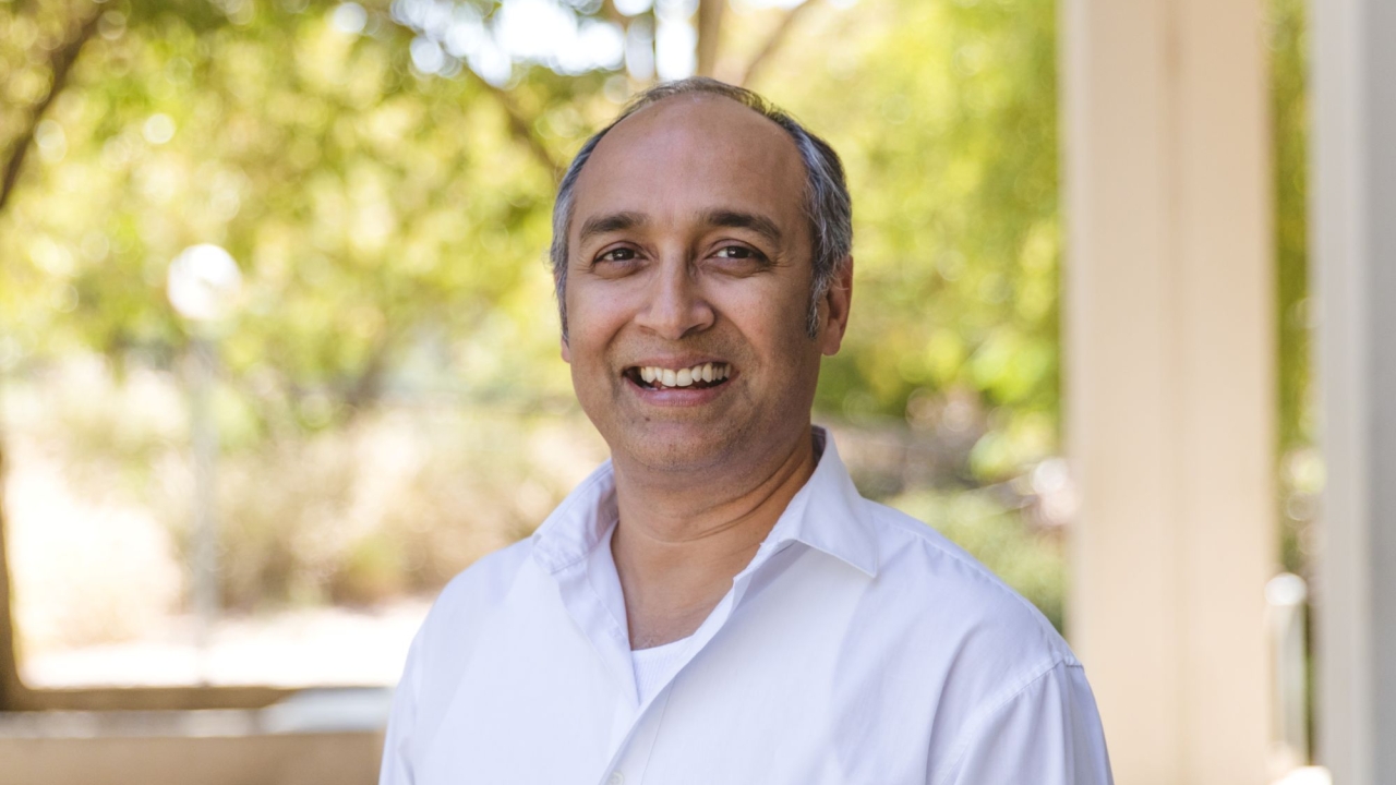 Sen in white shirt with blurred trees in background