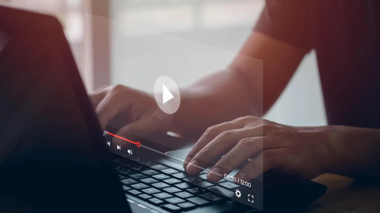 Hands on a laptop with a video on a screen 