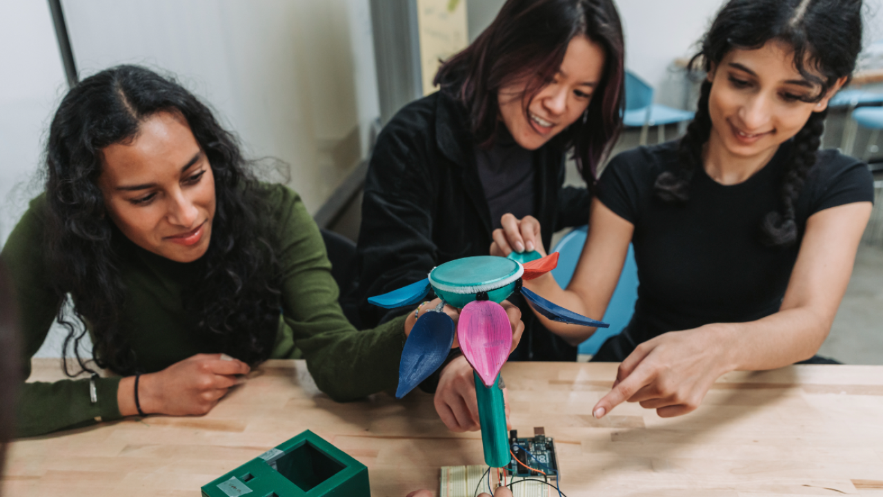 Anika Chand, Instructor Vivian Vuong, and Megha Mishra, work on the petal folding mechanic