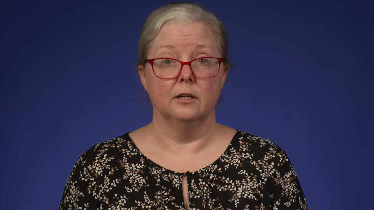 A professor speaking passionately on a purple backdrop