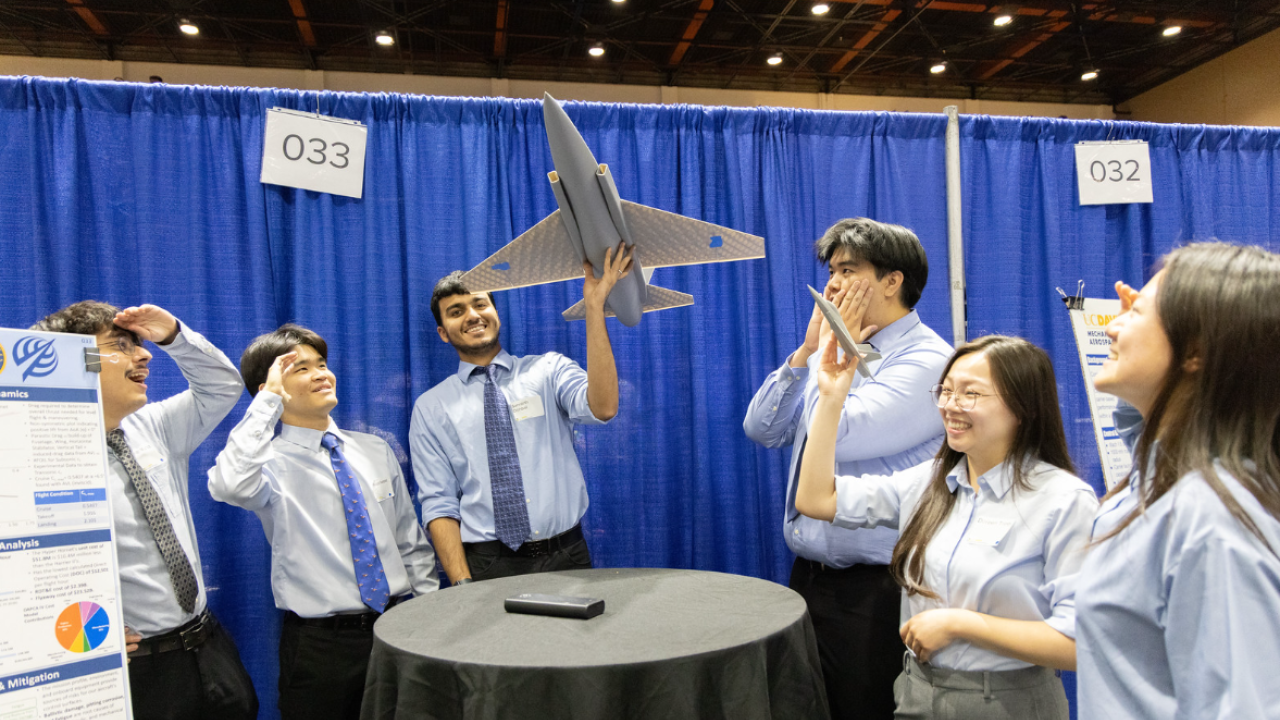 Students in light-blue shirts admire a model airplane at the UC Davis Engineering Design Showcase