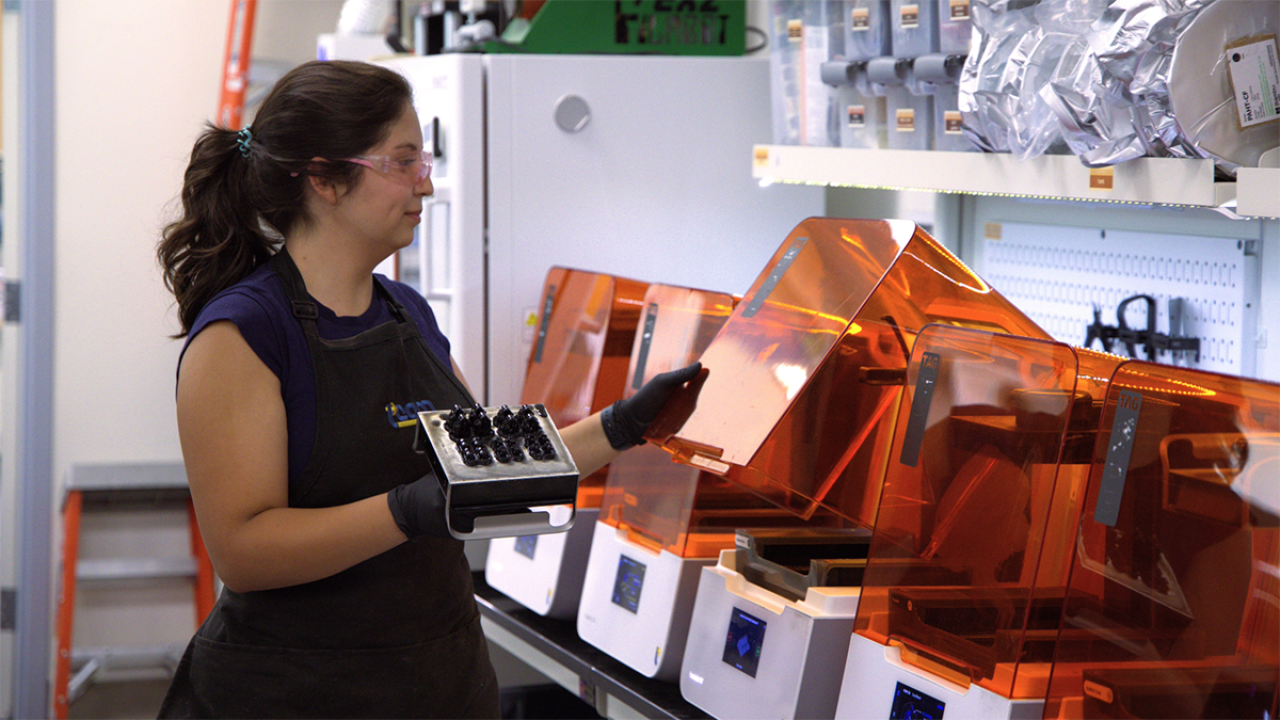 Valerie Quiroz working with orange 3D printers