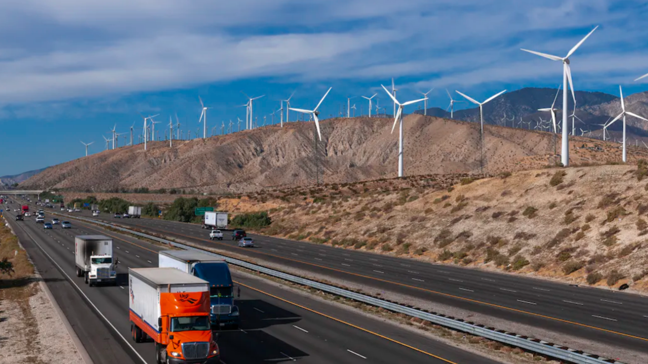 Highway with cars and trucks and hills with wind turbines