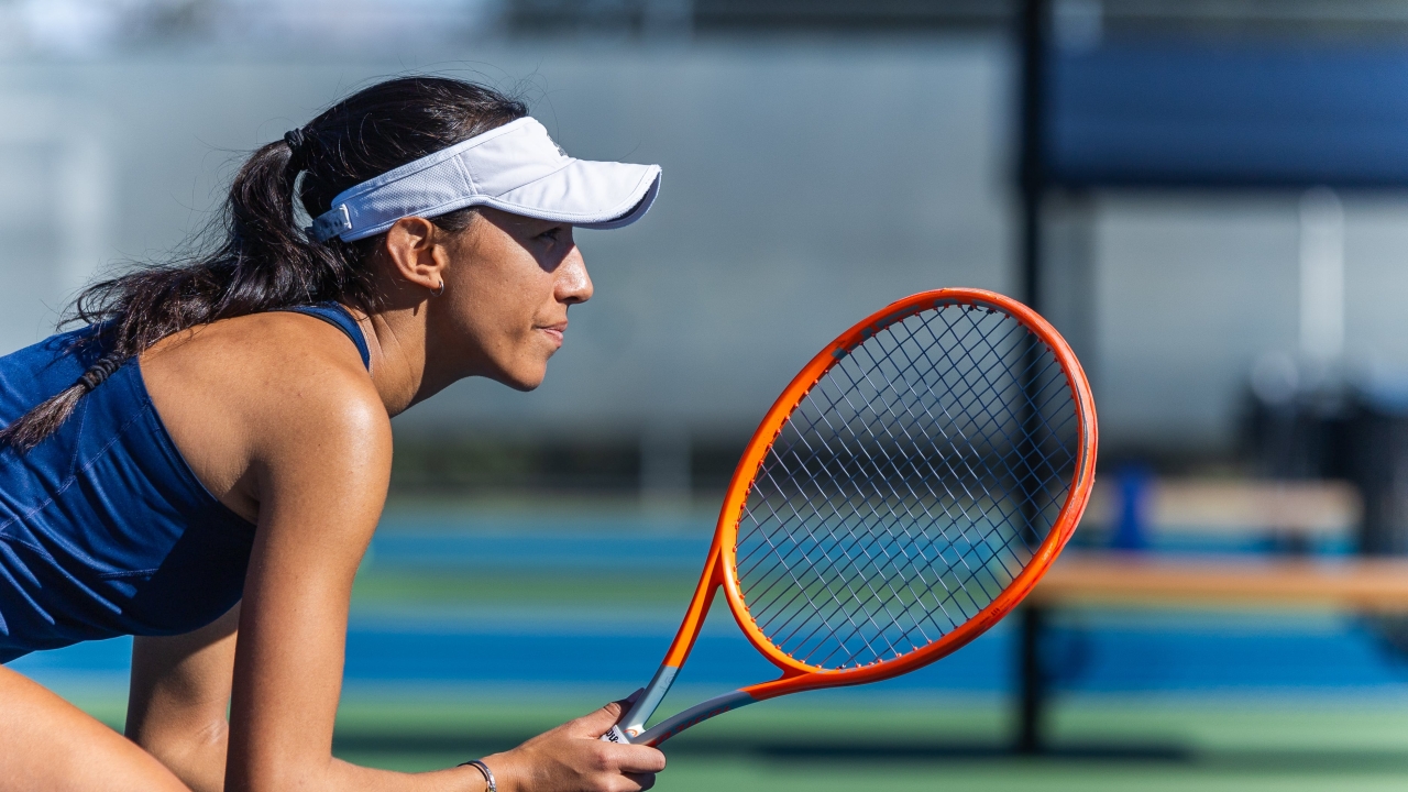 Kaia Wolfe crouching with a tennis racket