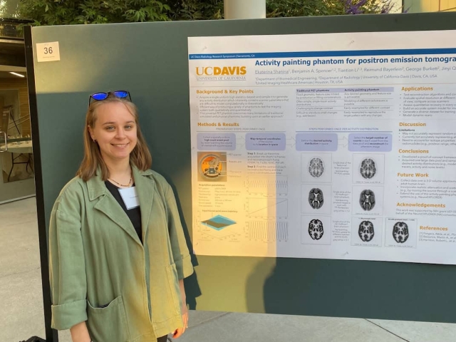 Ekaterina stands next to poster