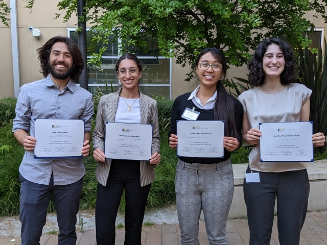 Anna Rita and trainee awardees outdoors in front of tree holding certificate awards