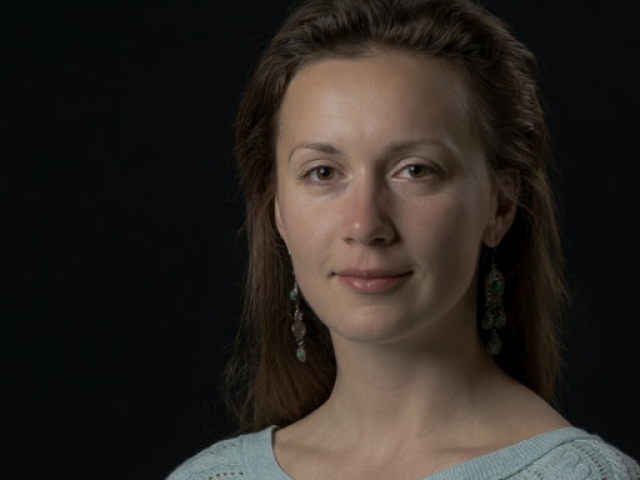 Low-key studio portrait of woman in sweater, neutral expression